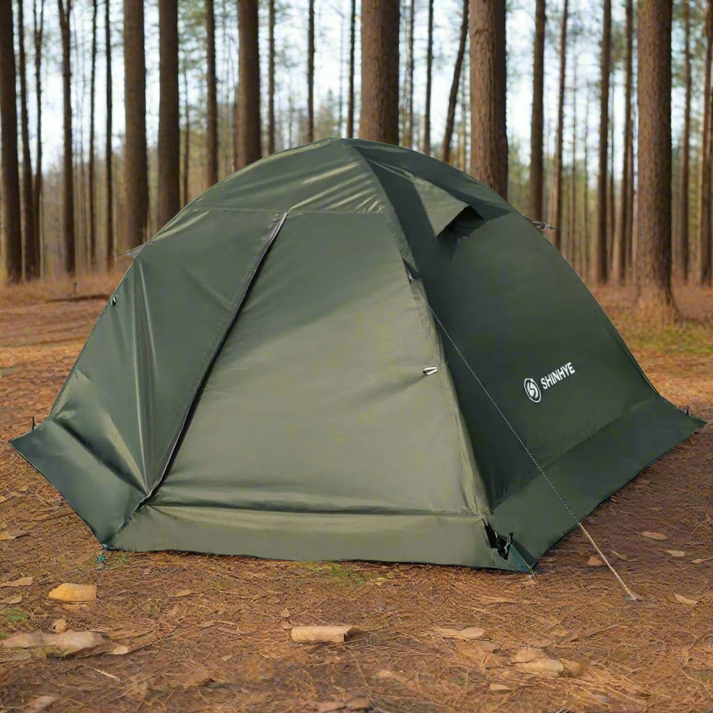 green tent with woods in background